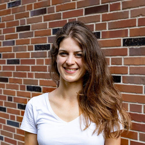 Moderatorin Anna Scheffold stehendes Portrait vor Backsteinwand